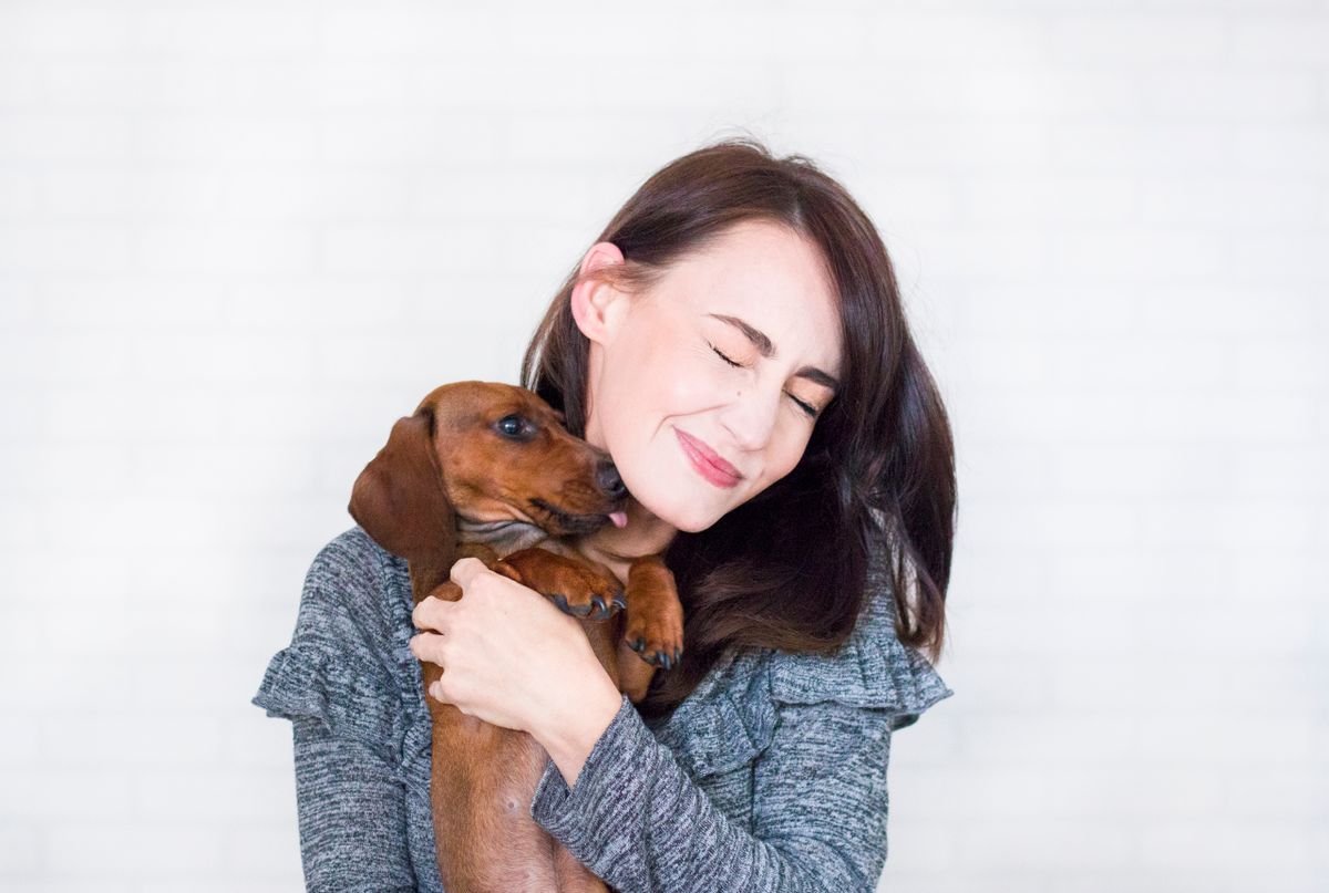 Woman smiling while holding a Dachshund puppy close